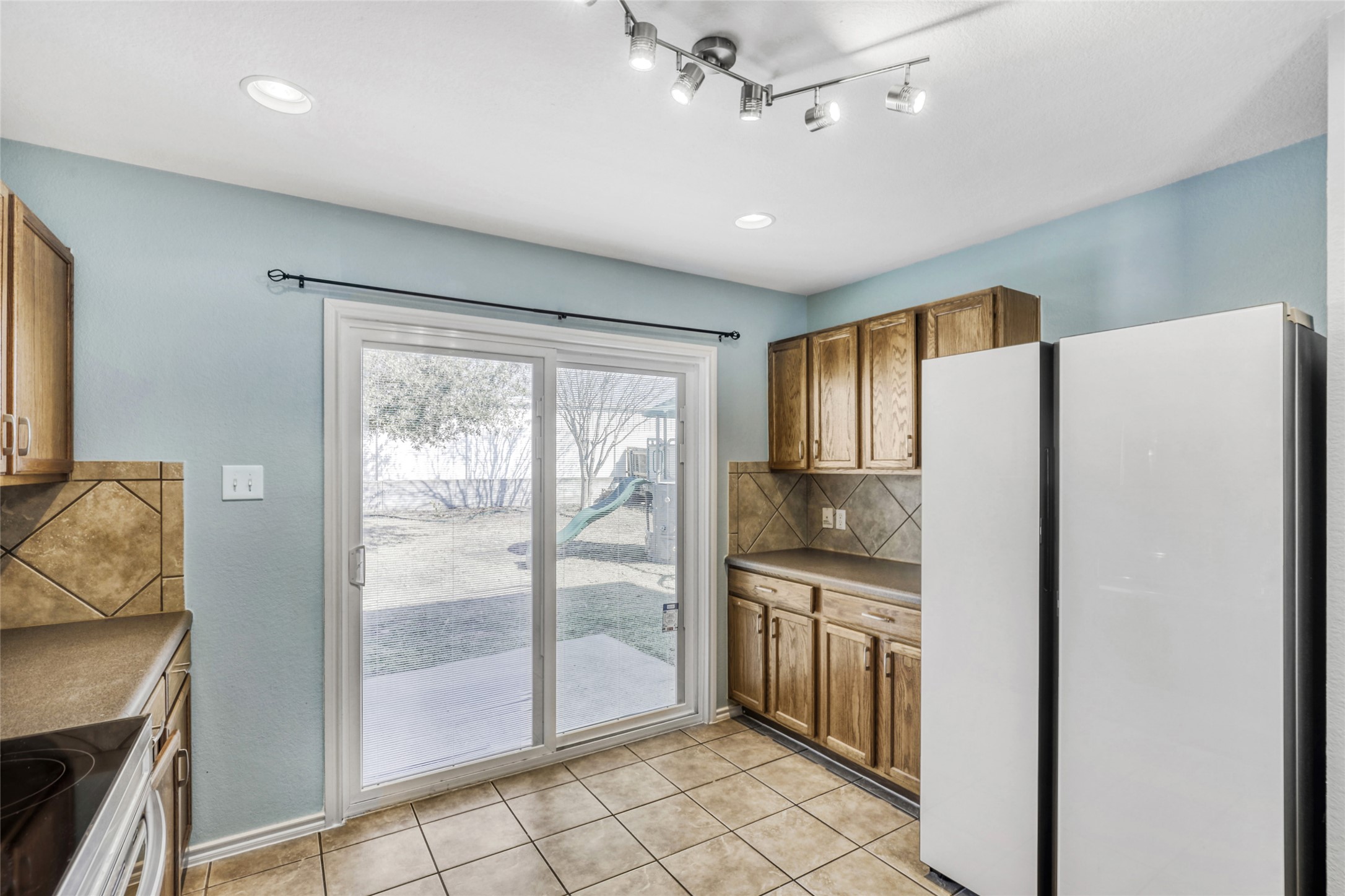 5624 Colinton Avenue Austin, TX 78754 - Photo 17 of 38 Kitchen featuring freestanding refrigerator, decorative backsplash, wood finish cabinetry, range with electric cooktop