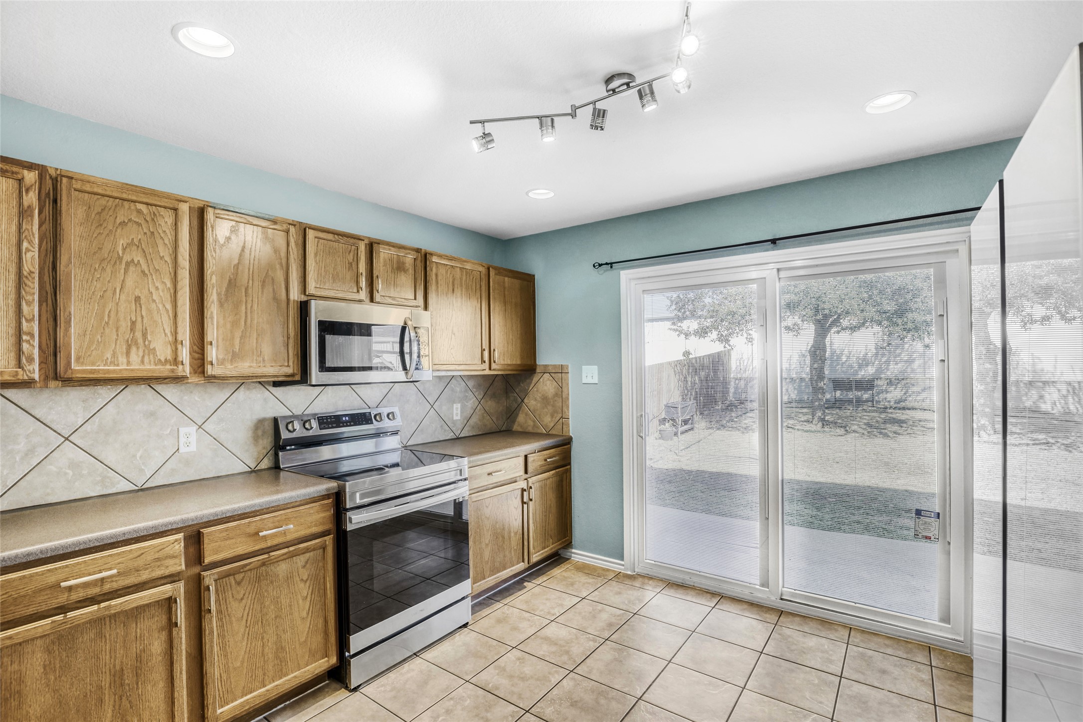5624 Colinton Avenue Austin, TX 78754 - Photo 2 of 38 Kitchen featuring stainless steel appliances, wood finish cabinets, tasteful backsplash, light tile patterned flooring, and recessed lighting