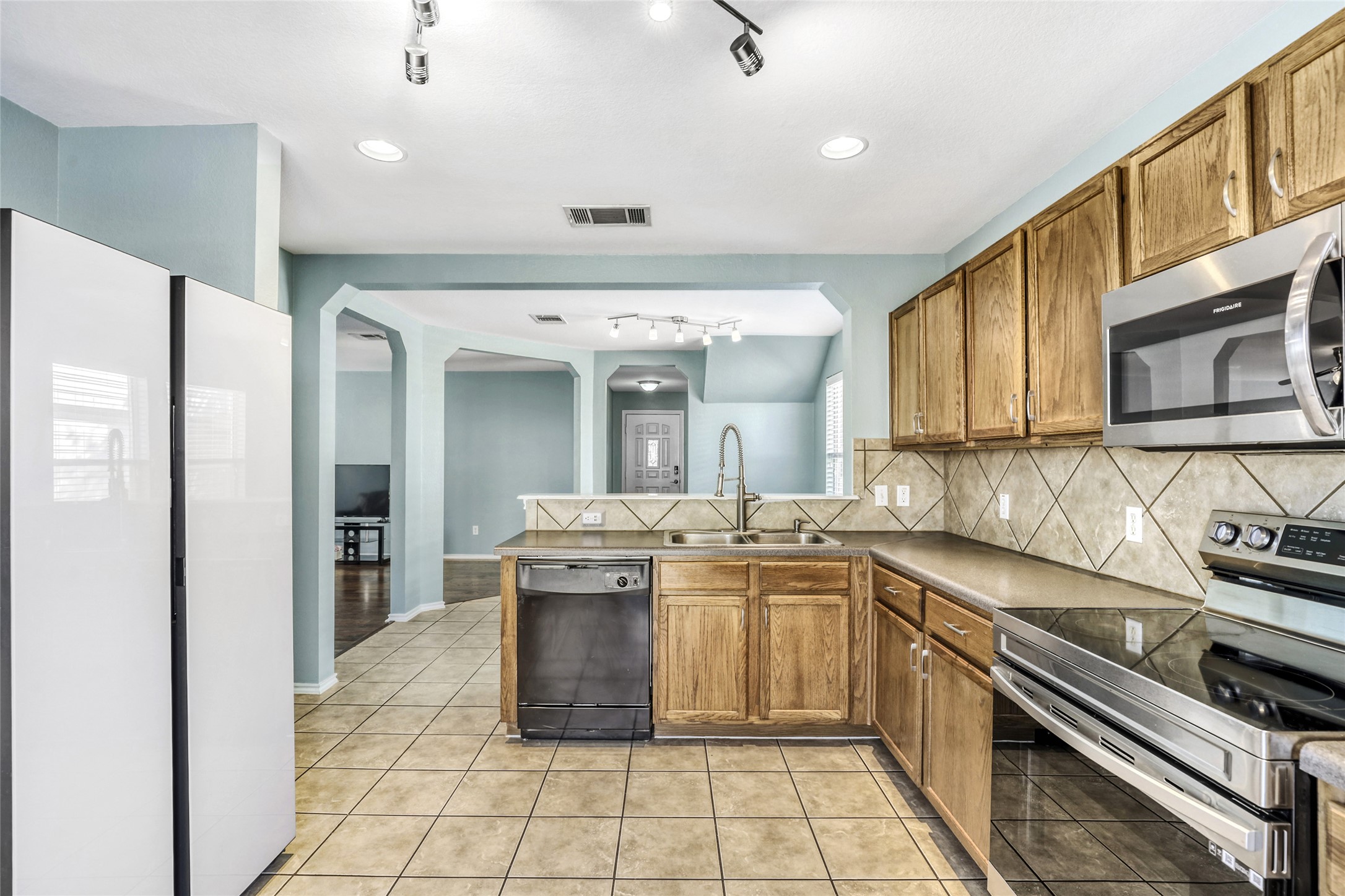 5624 Colinton Avenue Austin, TX 78754 - Photo 4 of 38 Kitchen featuring stainless steel appliances, arched walkways, track lighting, wood finish cabinetry, and a peninsula