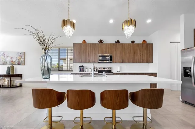 a kitchen with granite countertop a counter space chairs stainless steel appliances and cabinets