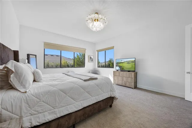 a spacious bedroom with a bed and a flat tv screen on a dresser