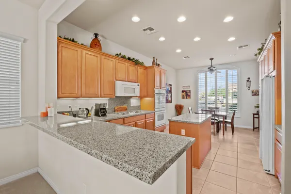 a kitchen with stainless steel appliances granite countertop a refrigerator top oven a sink a dining table and chairs