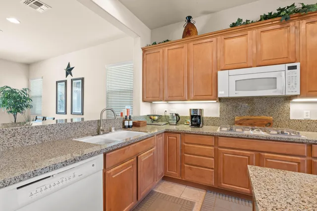 a kitchen with granite countertop a sink dishwasher stove and cabinets with wooden floor