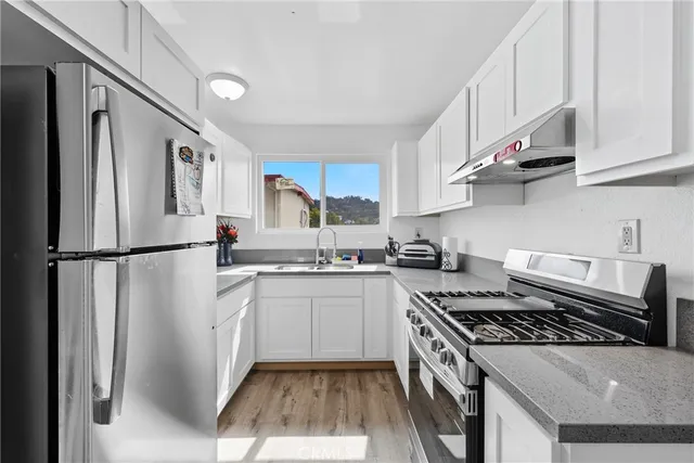 a kitchen with stainless steel appliances granite countertop a stove a refrigerator and a white cabinets