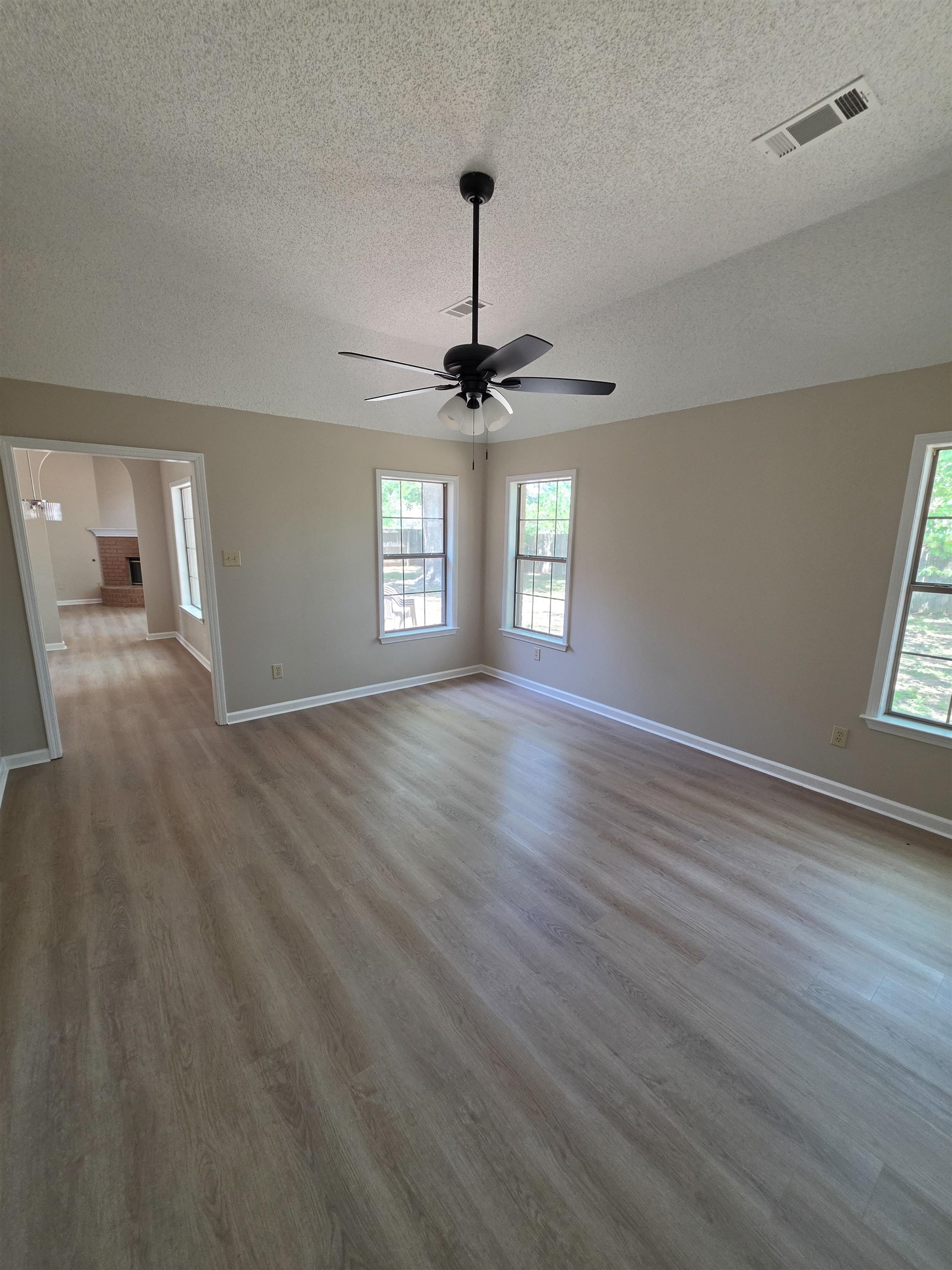 5570 Patsy Circle West Memphis, TN 38125 - Photo 11 of 22 Empty room featuring light wood-type flooring, healthy amount of natural light, a textured ceiling, a ceiling fan, and arched walkways