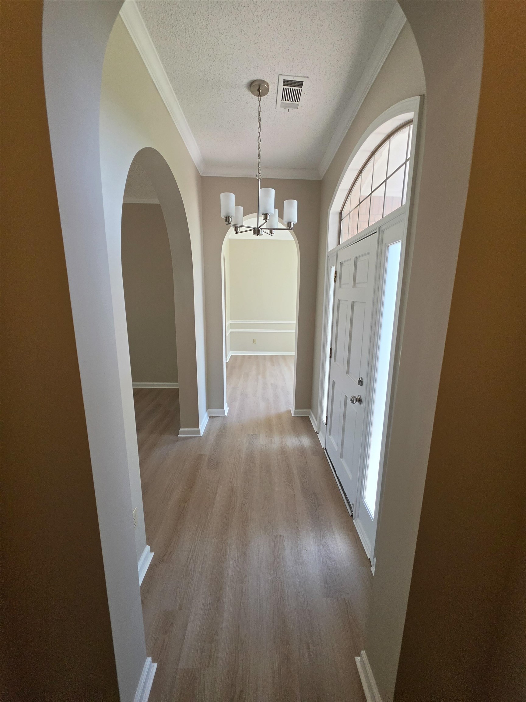5570 Patsy Circle West Memphis, TN 38125 - Photo 4 of 22 Foyer with arched walkways, suspended lighting, a textured ceiling, crown molding, and light wood-style floors
