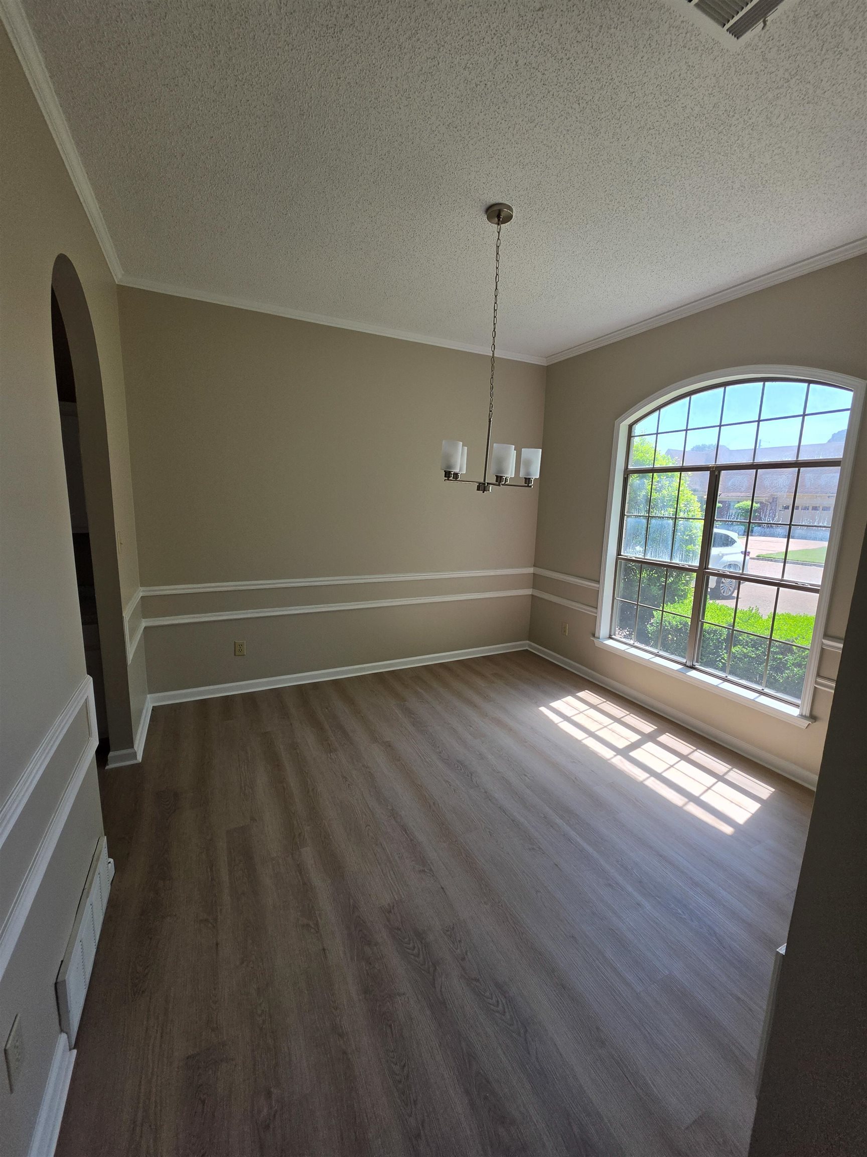 5570 Patsy Circle West Memphis, TN 38125 - Photo 5 of 22 Dining area featuring arched walkways, ornamental molding, a textured ceiling, light wood finished floors, and hanging lights