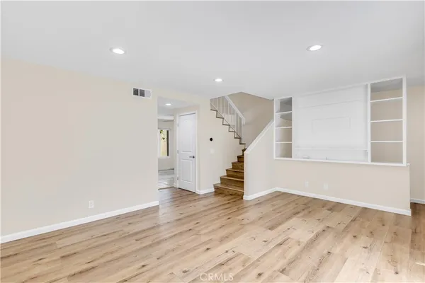 an empty room with wooden floor ceiling fan and windows
