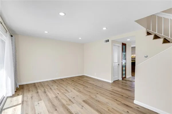 an empty room with wooden floor fan and windows