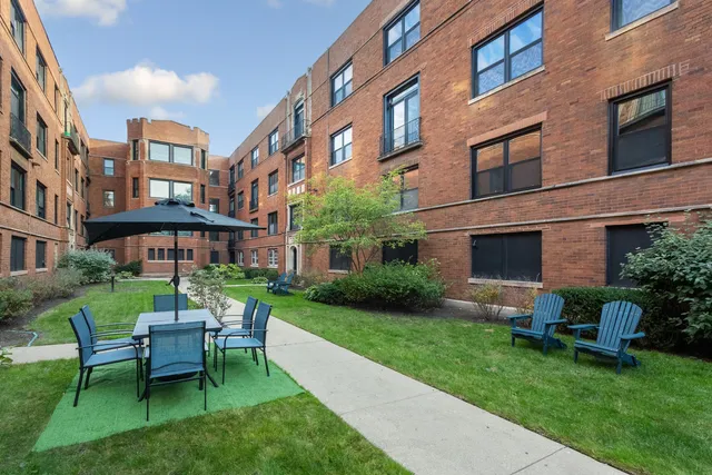 a view of a brick house with a yard patio and a table and chairs