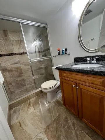 a bathroom with a granite countertop sink toilet and mirror