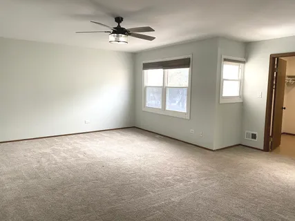 an empty room with windows and chandelier fan