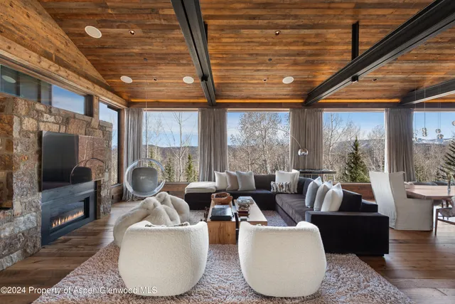 a living room with furniture a flat screen tv and floor to ceiling window