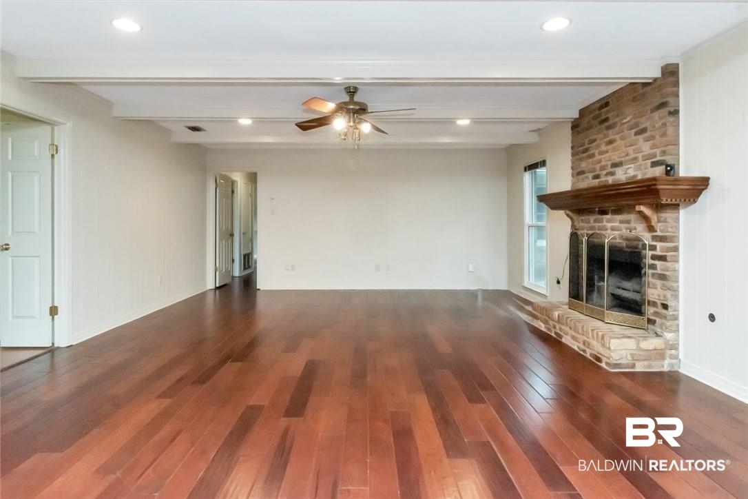 6109 Timberly Road North Mobile, AL 36609 - Photo 9 of 26 Unfurnished living room featuring a fireplace, beam ceiling, dark hardwood / wood-style floors, and ceiling fan