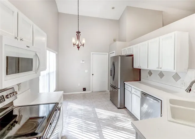 a kitchen with a refrigerator a stove and white cabinets