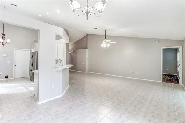an empty room with a fireplace and chandelier fan