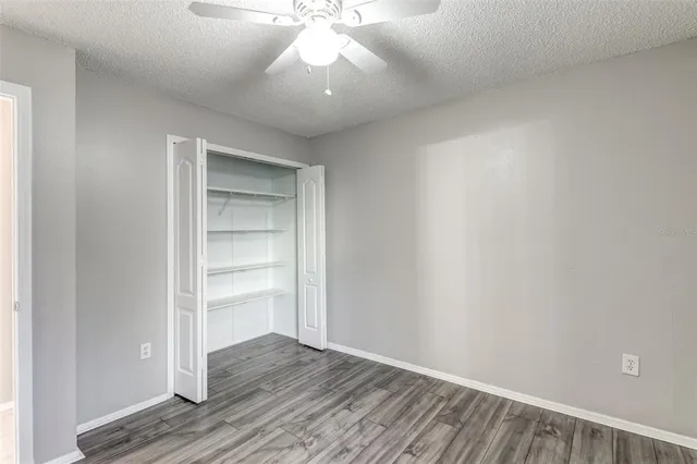 a view of an empty room with chandelier fan and wooden floor