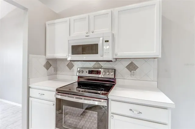 a kitchen with white cabinets and stainless steel appliances