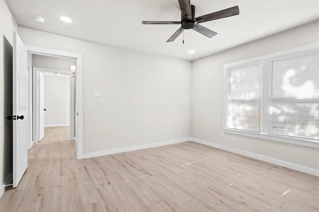 a view of empty room with wooden floor and fan