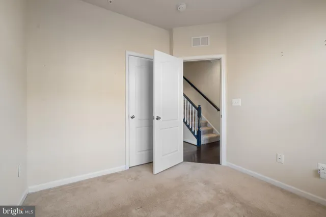 a view of an empty room with kitchen and entryway