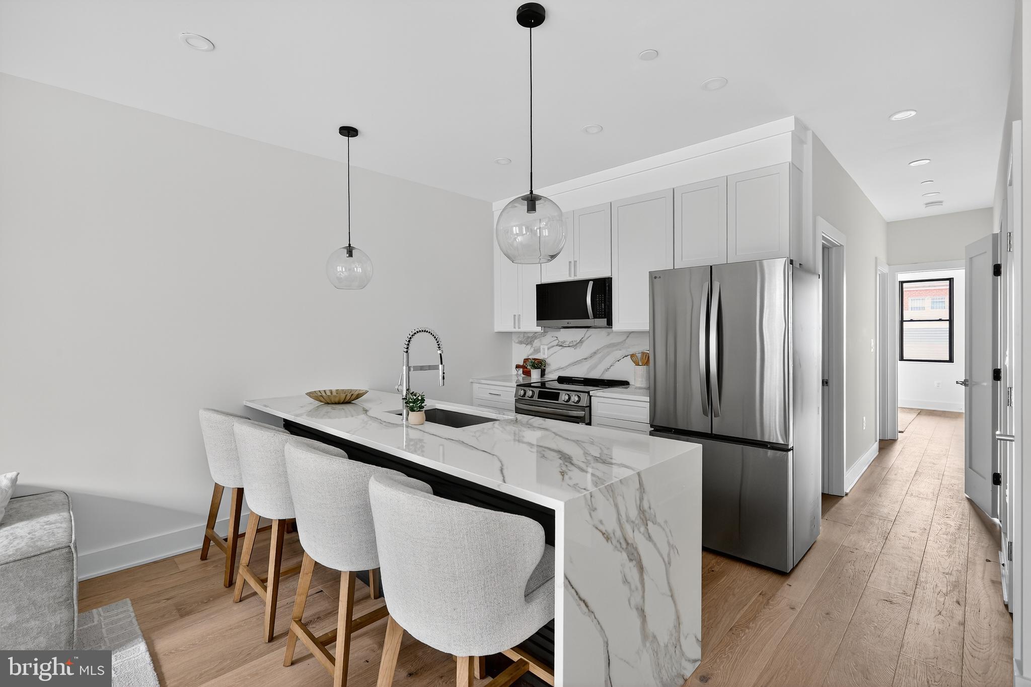 828 21st Street Northeast, Unit 1 Washington, DC 20002 - Photo 13 of 30 a kitchen with stainless steel appliances a dining table chairs a refrigerator and a chandelier