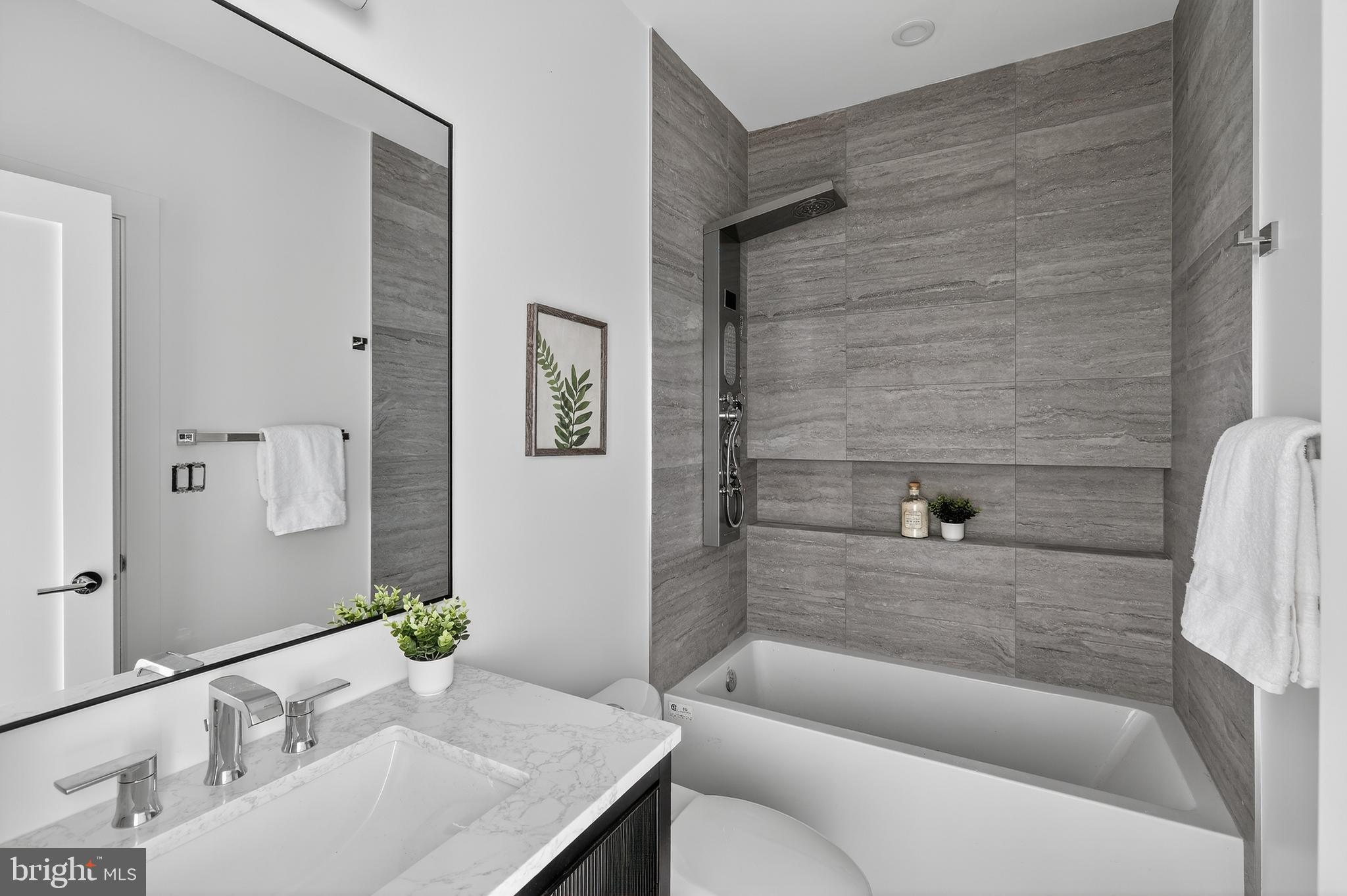 828 21st Street Northeast, Unit 1 Washington, DC 20002 - Photo 22 of 30 a bathroom with a granite countertop bathtub shower sink and toilet