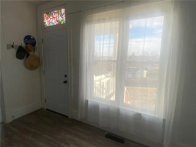 a view of an empty room with wooden floor and windows