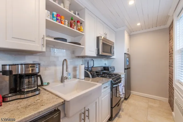 a kitchen with stainless steel appliances a stove a sink a microwave a refrigerator and cabinets