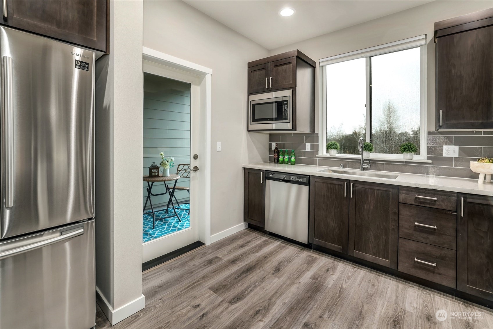 12718 35th Avenue Southeast, Unit E2 Everett, WA 98208 - Photo 14 of 28 a kitchen with stainless steel appliances granite countertop a refrigerator a sink dishwasher and wooden cabinets with wooden floor