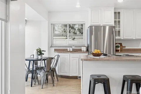 a kitchen with stainless steel appliances a white table chairs and a refrigerator