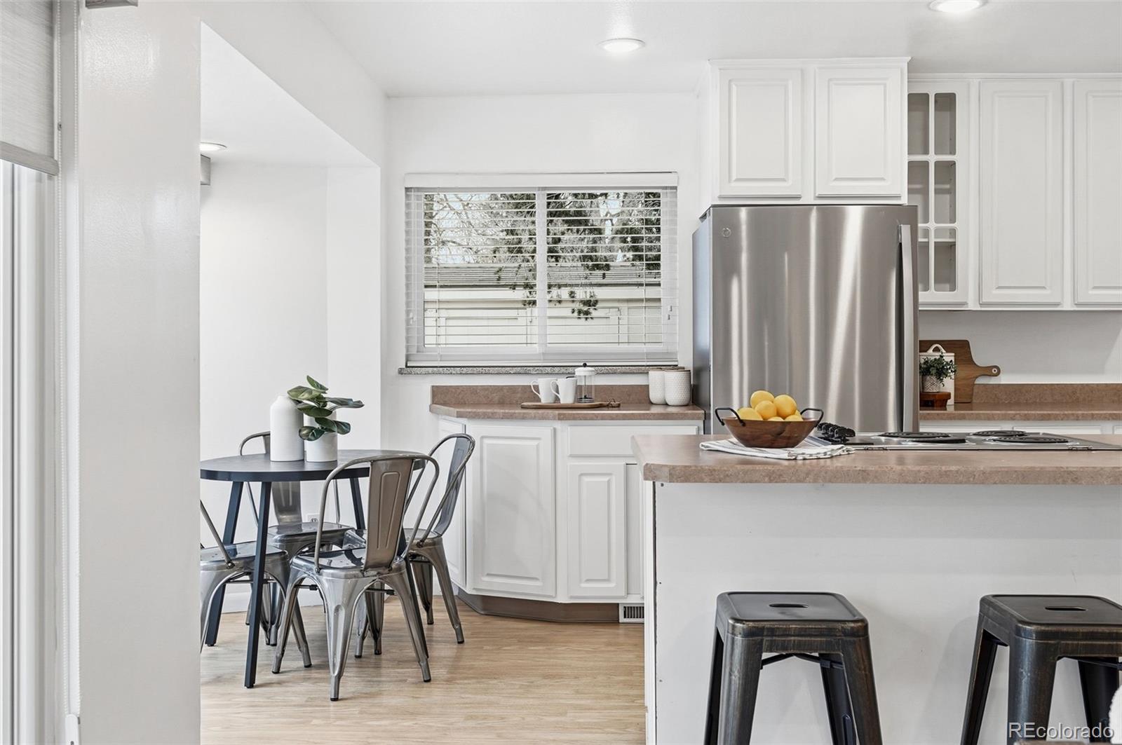 800 East Pinewood Avenue Littleton, CO 80121 - Photo 11 of 42 a kitchen with stainless steel appliances a white table chairs and a refrigerator