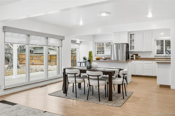 a kitchen with stainless steel appliances kitchen island granite countertop a table chairs sink and cabinets