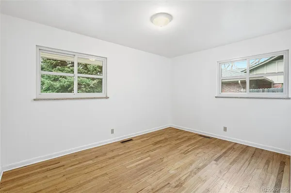 an empty room with wooden floor and windows