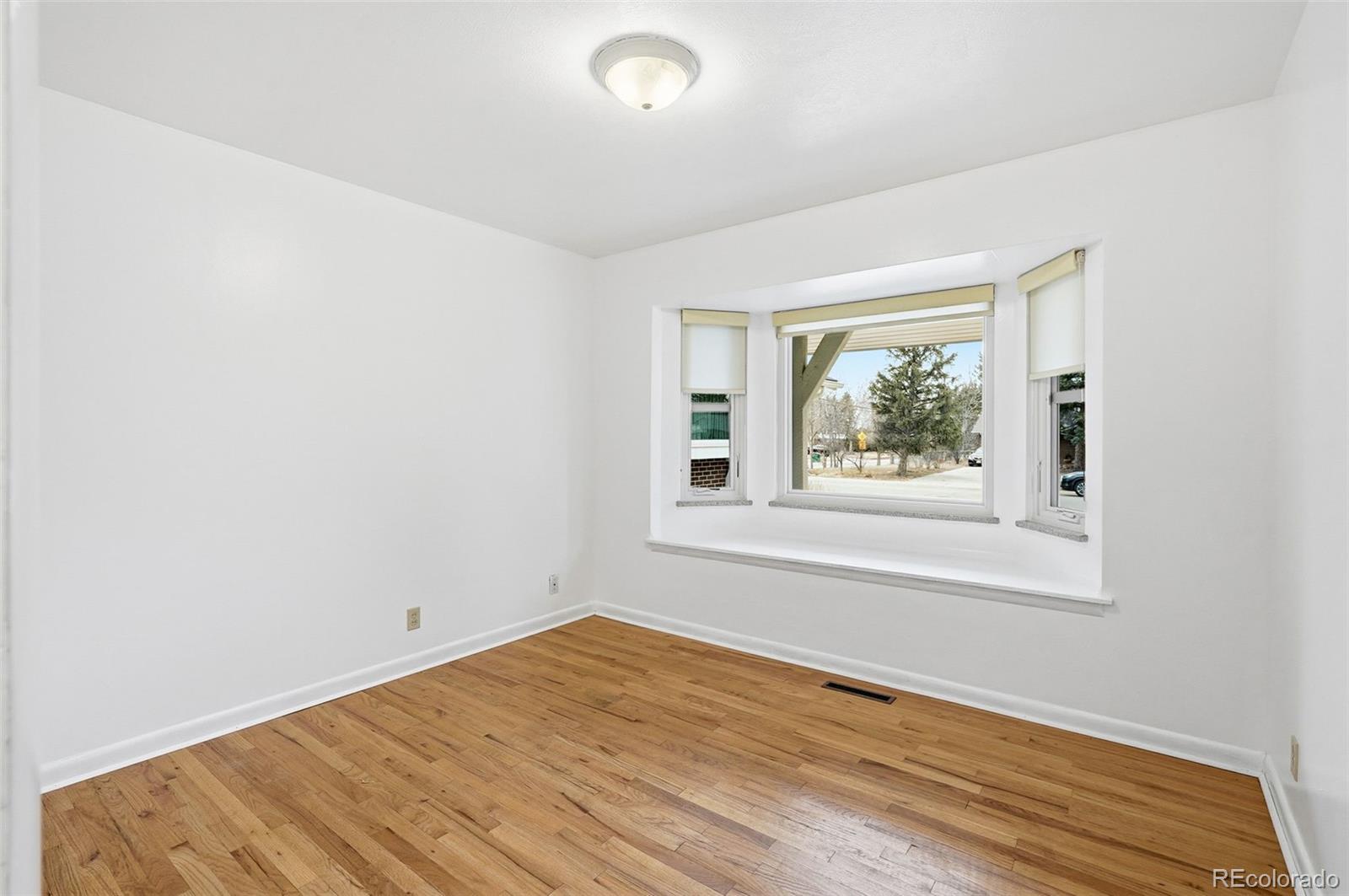 800 East Pinewood Avenue Littleton, CO 80121 - Photo 31 of 42 an empty room with wooden floor and windows