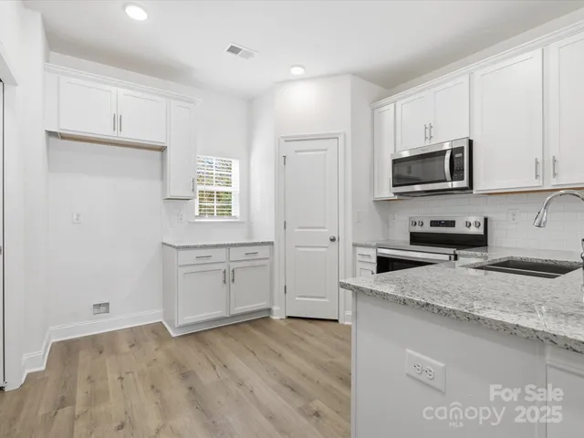 a kitchen with granite countertop white cabinets and stainless steel appliances