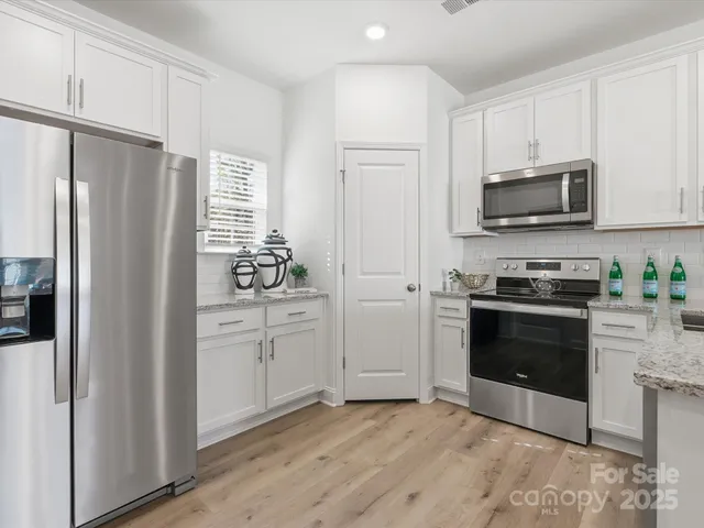 a kitchen with granite countertop a refrigerator and a stove top oven