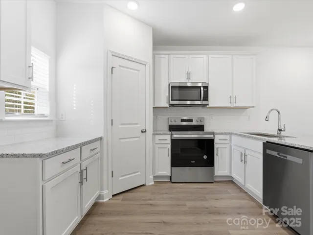 a kitchen with granite countertop white cabinets and stainless steel appliances
