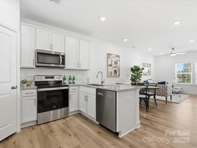 a kitchen with stainless steel appliances kitchen island granite countertop a stove top oven a sink a dining table and chairs