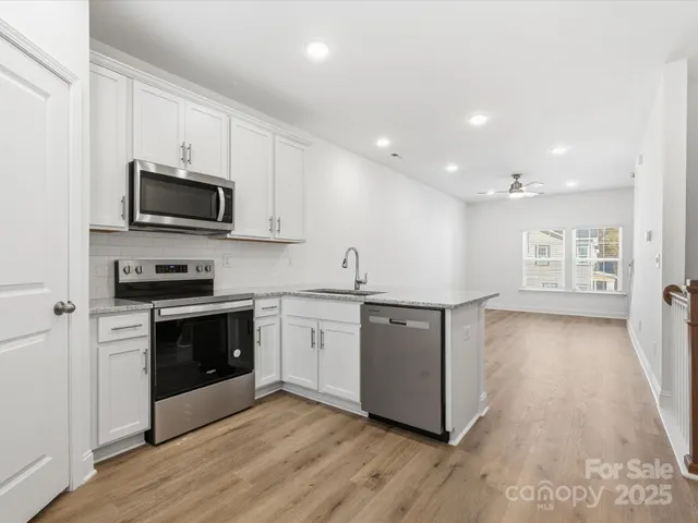 a kitchen with granite countertop a stove top oven a sink dishwasher a refrigerator and a microwave oven with wooden floor