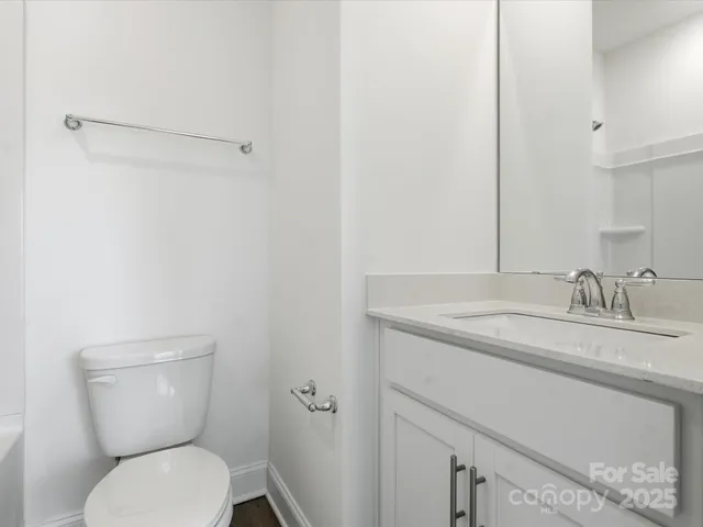 a bathroom with a toilet sink vanity and mirror