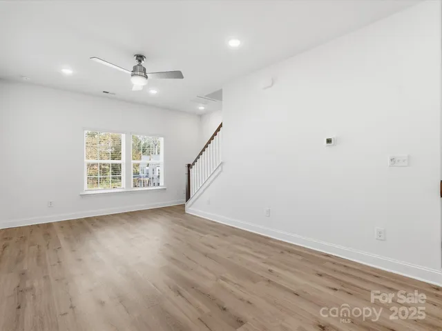 an empty room with wooden floor fan and windows