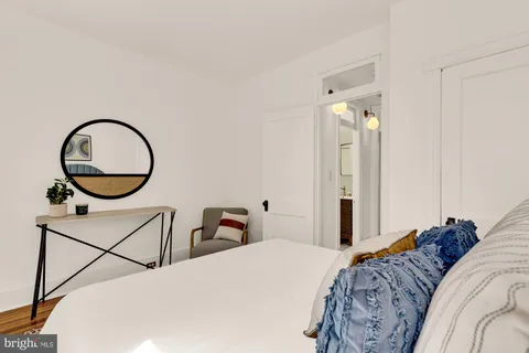 a bedroom with bed a mirror and a window