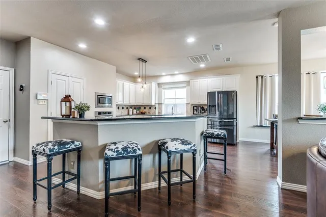 a kitchen with stainless steel appliances granite countertop a table chairs refrigerator and sink