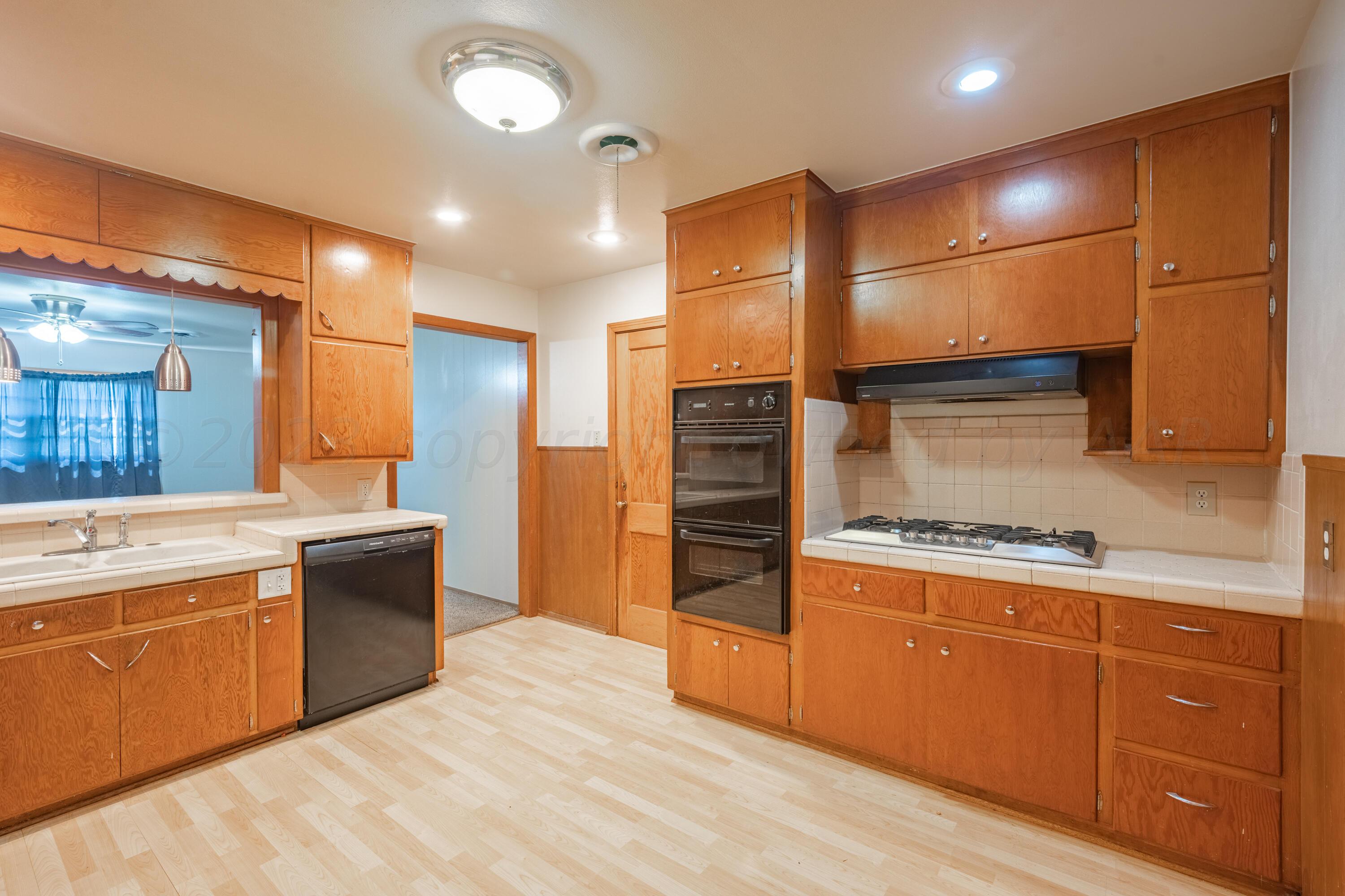 3616 South Travis Street Amarillo, TX 79110 - Photo 12 of 26 a kitchen with stainless steel appliances granite countertop a sink and cabinets with wooden floors