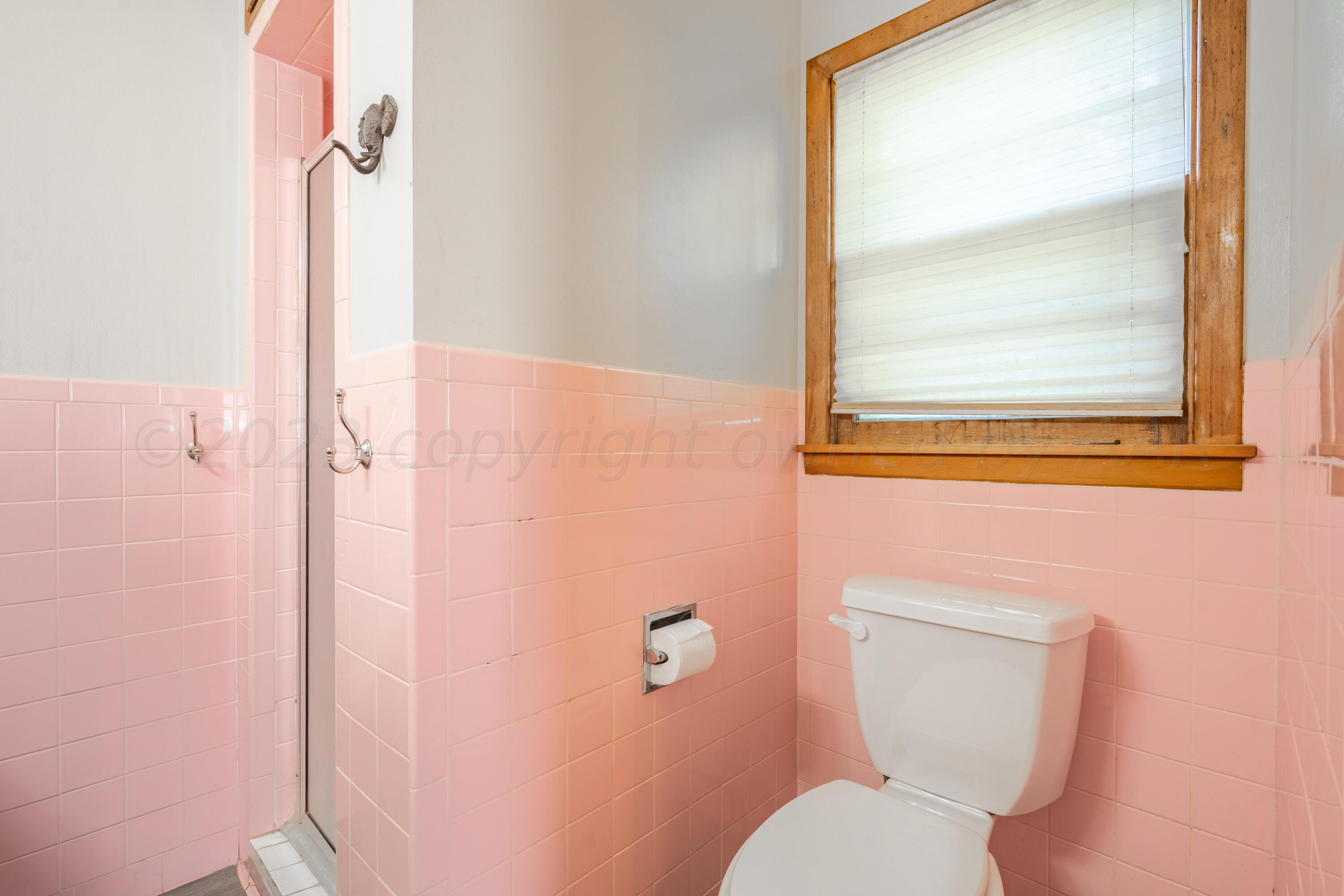 3616 South Travis Street Amarillo, TX 79110 - Photo 18 of 26 a bathroom with a toilet a sink and a window