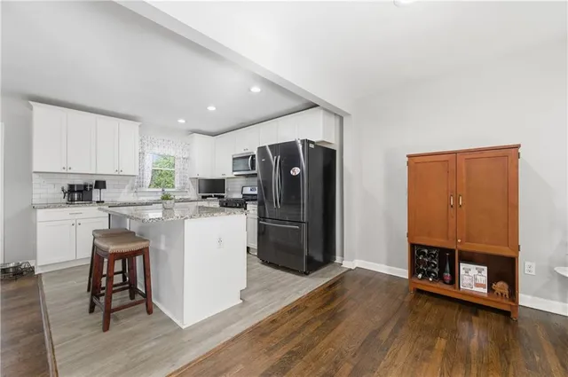 a kitchen with a refrigerator a stove and a microwave oven on the wooden floor