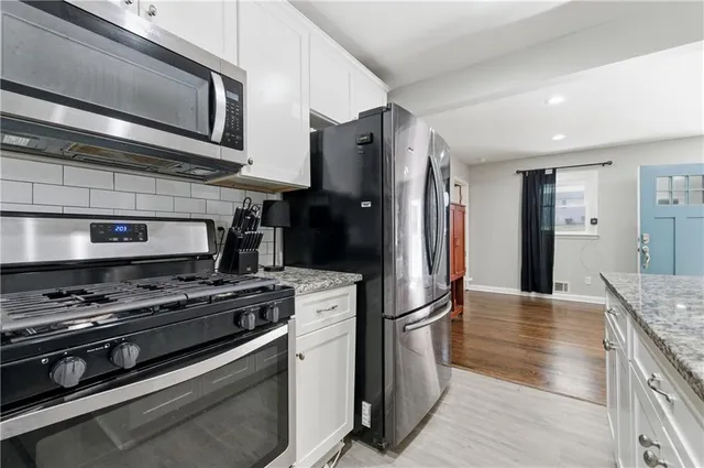 a kitchen with stainless steel appliances granite countertop a stove refrigerator and microwave