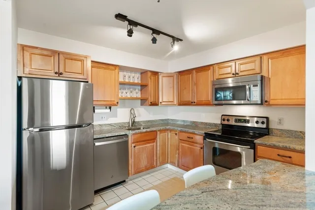 a kitchen with stainless steel appliances granite countertop a refrigerator a stove a sink dishwasher a refrigerator with white cabinets and wooden floor