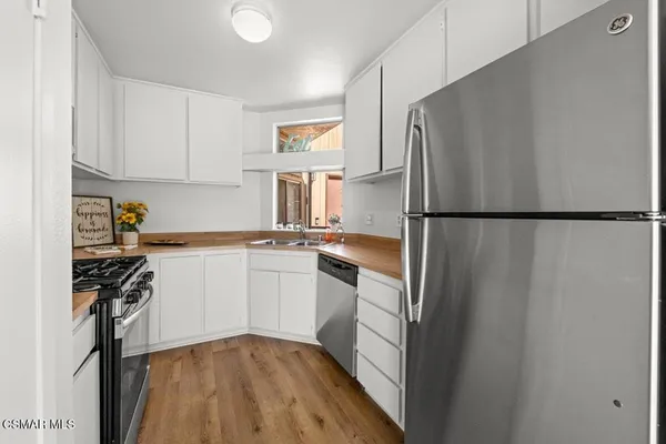 a kitchen with a refrigerator a stove top oven a sink and cabinets