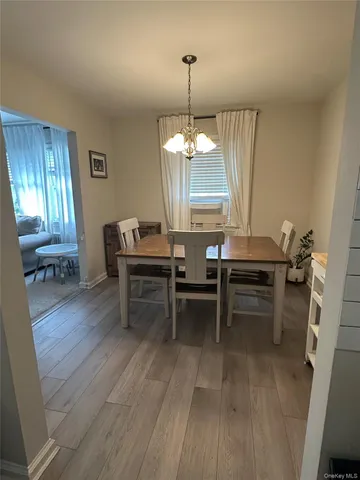 a dining room with wooden floor a chandelier a wooden table and chairs